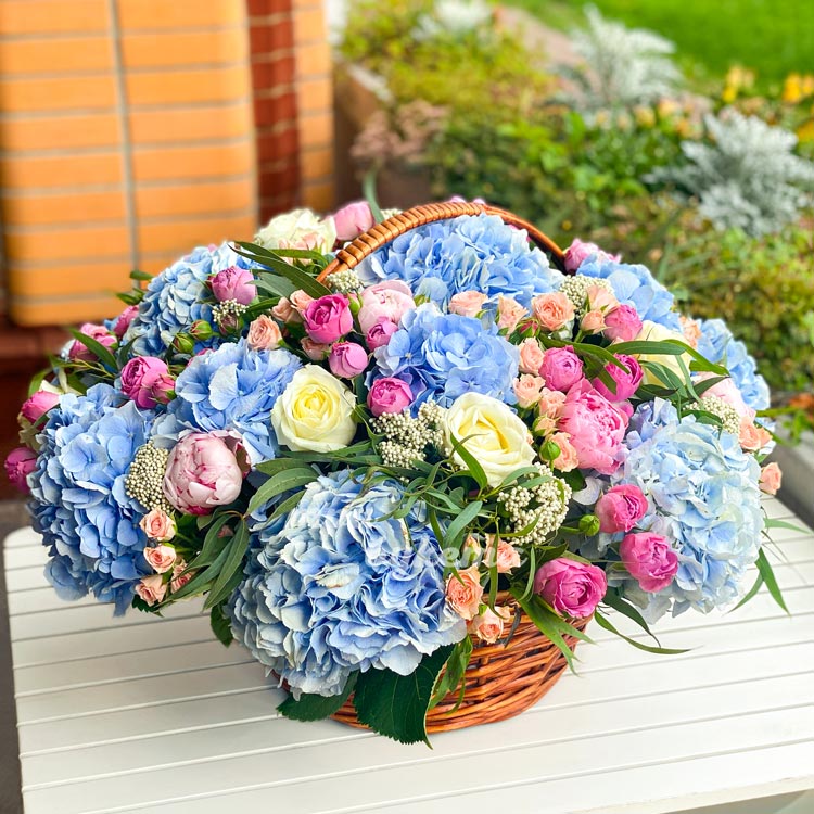 Корзина синих гортензий и роз (на белом столе)